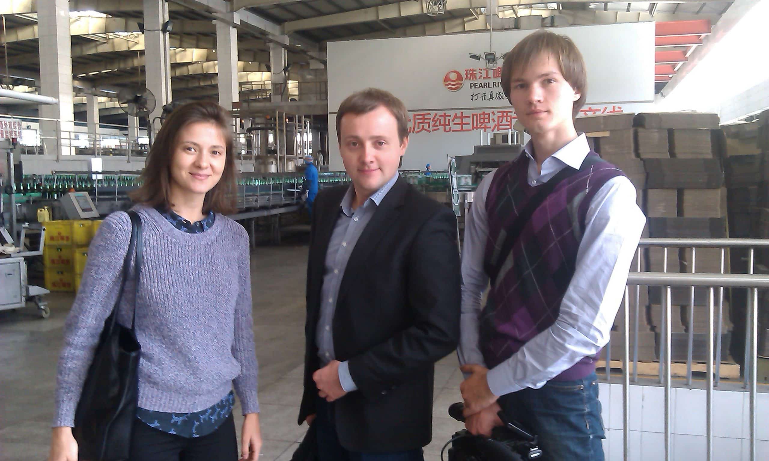 Anna with two clients beside a factory production line