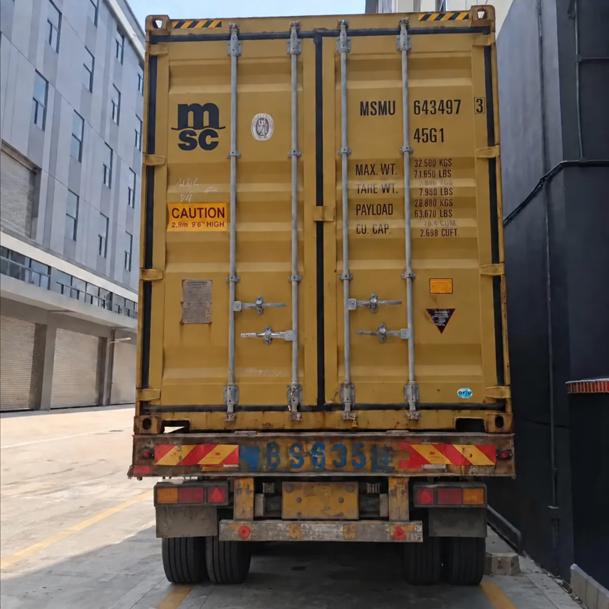A yellow shipping container outside warehouse buildings